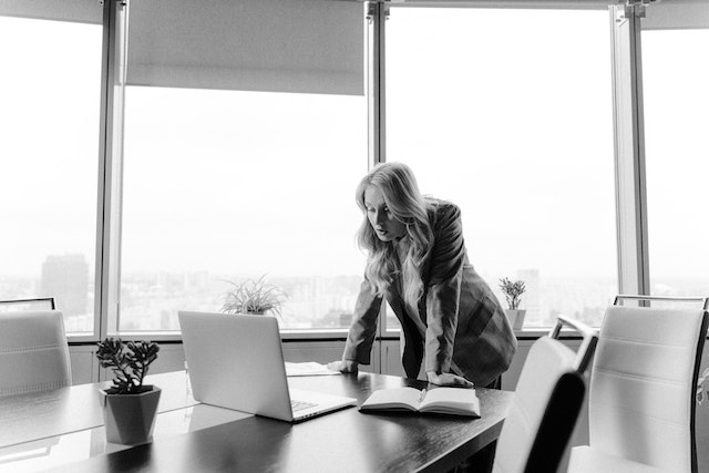 Confident woman standing at office desk – representing the bold, driven personality of the Aries zodiac sign