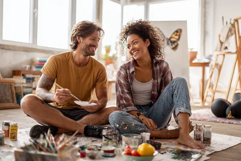 Happy couple painting together in an art studio, symbolizing the 5th to 7th houses of astrology—creativity, health routines, and relationships.