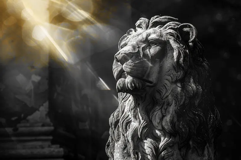 Stone lion statue with golden sunlight rays, symbolizing Leo woman traits and the zodiac’s regal strength and solar power