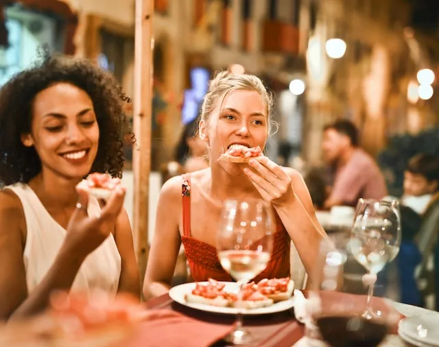 Friends enjoying dinner together at a lively restaurant, reflecting the energetic, social, and adventurous spirit often associated with Aries personality traits.