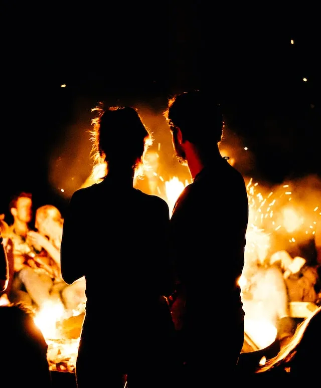 Couple standing beside a glowing bonfire at night, reflecting the passionate energy, excitement, and adventurous spirit often associated with Aries and Leo compatibility.
