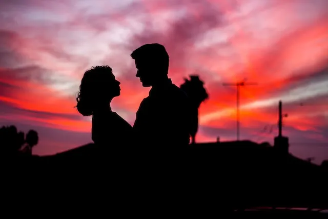Silhouette of a couple embracing beneath a vibrant sunset sky, representing the balance, romance, and emotional harmony often associated with Aries and Libra compatibility.