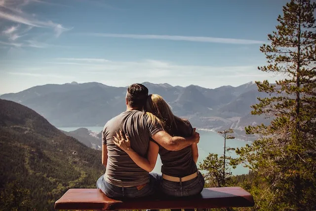 Capricorn and Cancer couple embracing while overlooking a peaceful mountain lake, symbolizing the loyal, supportive, and emotionally balanced compatibility between Capricorn and Cancer.