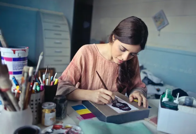 Capricorn woman carefully painting intricate artwork, symbolizing the discipline, patience, precision, and determination that define the Capricorn personality.