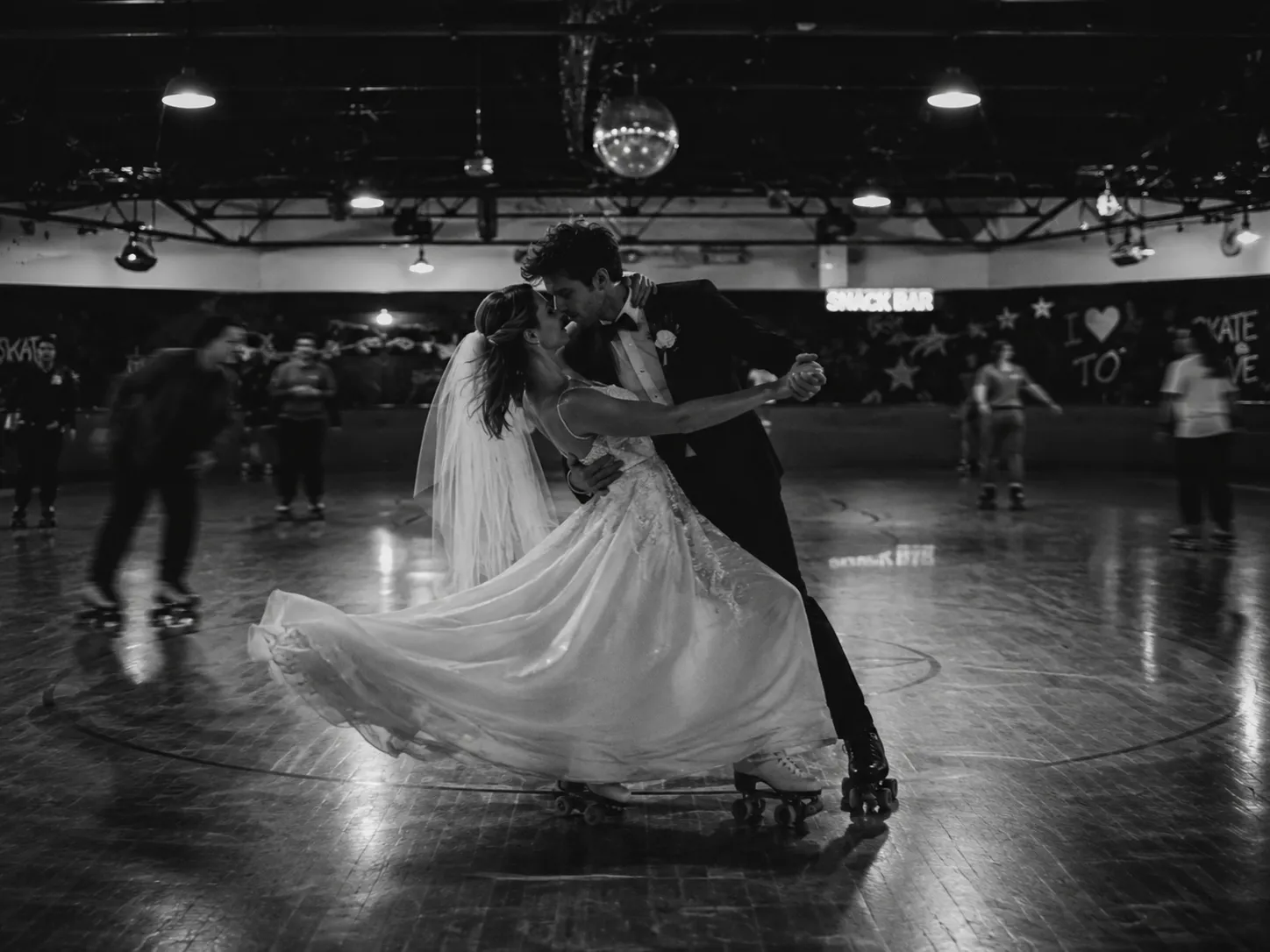 Black-and-white artistic photograph of a bride and groom roller skating together in a vintage rink, symbolizing Scorpio's passionate, unconventional, and deeply committed approach to love and relationships.